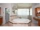Spacious bathroom with tub, glass block shower, and vanity with oak cabinets and granite countertops at 916 Bunker View Dr, Apollo Beach, FL 33572