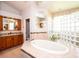Inviting bathroom with tub, glass block shower, and oak vanity with granite countertops at 916 Bunker View Dr, Apollo Beach, FL 33572