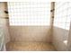 Bright walk-in shower featuring glass block window and tan tile walls at 916 Bunker View Dr, Apollo Beach, FL 33572
