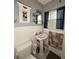 Bathroom features a pedestal sink, decorative mirror, and blue-patterned window curtain at 114 N Arcturas Ave, Clearwater, FL 33765