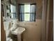 Bathroom featuring pedestal sink, window with patterned curtain, and tiled walls at 114 N Arcturas Ave, Clearwater, FL 33765