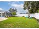 Lush backyard with a manicured lawn, landscaping, and a screened-in pool for outdoor enjoyment at 1251 Fairway Dr, Dunedin, FL 34698