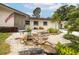 Landscaped front yard with rock water feature, decorative rocks and plants and a stone and siding facade at 1251 Fairway Dr, Dunedin, FL 34698