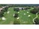 Aerial view of a lush golf course with manicured greens, sand traps, and a serene lake at 12713 Grand Traverse Dr, Dade City, FL 33525