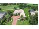 Aerial view of a tile roof house featuring a red brick driveway, a manicured lawn, palm trees, and a golf course view at 12713 Grand Traverse Dr, Dade City, FL 33525