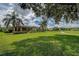 Expansive backyard with manicured lawn, mature trees, and a glimpse of the golf course at 12713 Grand Traverse Dr, Dade City, FL 33525
