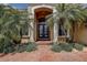 Beautiful home entrance with black double doors, white columns, and lush landscaping with small flowers at 12713 Grand Traverse Dr, Dade City, FL 33525