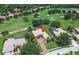 Aerial view of a golf home featuring mature trees, lush landscaping, and brick paved driveway at 12713 Grand Traverse Dr, Dade City, FL 33525