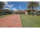 Elegant single-story home with a tile roof, lush landscaping, manicured lawn, and long brick driveway leading to the entrance at 12713 Grand Traverse Dr, Dade City, FL 33525