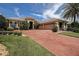 Charming single-story home featuring a three-car garage, brick driveway, lush landscaping, and a well-manicured lawn at 12713 Grand Traverse Dr, Dade City, FL 33525