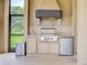 Functional outdoor kitchen area featuring a grill, sink, storage, and views of the surrounding landscape at 12713 Grand Traverse Dr, Dade City, FL 33525