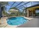 Inviting screened pool with an umbrella, surrounded by beautiful landscaping and a peek into the home's interior at 12713 Grand Traverse Dr, Dade City, FL 33525