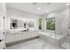Luxurious bathroom featuring marble accents, a soaking tub, and an illuminated mirror at 14617 Galt Lake Dr, Tampa, FL 33626