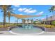 Community splash pool with sun shade, stone surround, palm trees and a distant building at 14617 Galt Lake Dr, Tampa, FL 33626
