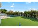 Large backyard with artificial turf, tropical landscaping, putting green, and perimeter fencing at 15415 Otto Rd, Tampa, FL 33624