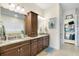 Bathroom featuring granite counters, dual sinks, vanity, and a walk-in closet at 15415 Otto Rd, Tampa, FL 33624