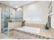 Bathroom featuring a soaking tub, glass shower, and neutral tile at 15415 Otto Rd, Tampa, FL 33624