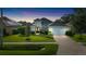 Stunning home exterior with lush landscaping, brick driveway, and manicured lawn at dusk at 15415 Otto Rd, Tampa, FL 33624