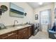 Well-equipped laundry room with modern washer, dryer, sink, cabinets, and granite countertop at 15415 Otto Rd, Tampa, FL 33624