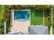 Aerial view of a backyard oasis with a sparkling pool, patio, and a putting green surrounded by lush tropical landscaping at 15415 Otto Rd, Tampa, FL 33624