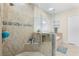 Bathroom with a shower featuring glass doors, beige tiles, and a built-in shelf at 15415 Otto Rd, Tampa, FL 33624
