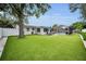Extensive backyard with artificial turf, pool, patio, privacy fence, and mature tree at 1557 77Th N Ave, St Petersburg, FL 33702