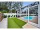 Screened-in pool with artificial turf surround, patio furniture, and well-maintained privacy fence at 1557 77Th N Ave, St Petersburg, FL 33702