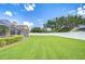 A large, green backyard with a white privacy fence, shrubs, and an enclosed pool area at 17302 Stetson Ln, Odessa, FL 33556