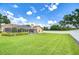 Spacious backyard with well-maintained lawn, white fence, and view of the screened-in pool area at 17302 Stetson Ln, Odessa, FL 33556