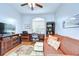 Cozy home office with a ceiling fan, desk, and comfortable orange sofa at 17302 Stetson Ln, Odessa, FL 33556
