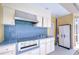 An outdoor kitchen with white cabinets, stainless steel grill, blue tile backsplash and an adjacent storage cabinet at 17302 Stetson Ln, Odessa, FL 33556