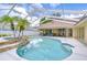A luxurious screened-in pool area with palm trees and a stone accent wall with an attached outdoor seating area at 17302 Stetson Ln, Odessa, FL 33556