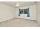 Spacious carpeted bedroom features a ceiling fan and a window with blue curtains at 1734 Mapleleaf Blvd, Oldsmar, FL 34677