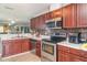 Well-lit kitchen boasts stainless steel appliances, cherry cabinets, mosaic backsplash, and granite countertops at 1827 Peaceful Palm St, Ruskin, FL 33570
