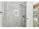 Bathroom boasts marble shower and an illuminated round mirror reflected in glass door at 2 S Treasure Dr, Tampa, FL 33609