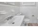 Bright bathroom features white tiles, sink, mirror, toilet, and linen shelves at 2509 W Crawford St, Tampa, FL 33614