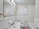 Bathroom features white tiled walls, toilet, sink, mirror, and combination tub and shower at 2509 W Crawford St, Tampa, FL 33614