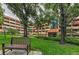 Building exterior featuring a bench, green lawn, and mature trees for a serene outdoor space at 3062 Eastland Blvd # 308, Clearwater, FL 33761