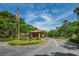 Community entrance featuring lush landscaping, a security gate and an American flag on a clear, blue-sky day at 3062 Eastland Blvd # 308, Clearwater, FL 33761
