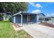 Charming blue home with a covered carport and cozy porch swing and fire pit at 3125 Beaver Creek Dr, Wesley Chapel, FL 33543