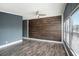 Bright living room featuring wood-look flooring, a ceiling fan, and a distinctive wood accent wall at 3125 Beaver Creek Dr, Wesley Chapel, FL 33543