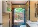 Bright bathroom with a glass shower door that has a view of the tropical outdoors and a modern sink at 3225 Rosery Ne Rd, Largo, FL 33771