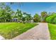 Beautiful exterior view of home featuring a well-manicured lawn, brick driveway and tropical plants at 3225 Rosery Ne Rd, Largo, FL 33771