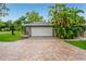 Exterior garage view showcasing a brick driveway, lawn and tropical landscaping at 3225 Rosery Ne Rd, Largo, FL 33771
