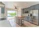 Bright kitchen featuring gray cabinetry, an island, stainless steel appliances, and a view of the pool at 3225 Rosery Ne Rd, Largo, FL 33771