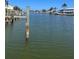 View of the canal and docks with calm water and tropical plants in the background at 326 Windrush Blvd # 103, Indian Rocks Beach, FL 33785