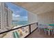 Balcony with table and chairs offering ocean views of the pristine beach and sparkling swimming pool below at 440 S Gulfview Blvd # 701, Clearwater Beach, FL 33767