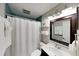 Fresh bathroom with white shower curtain, vanity, and a dark framed mirror at 4505 S Clark Ave, Tampa, FL 33611