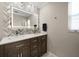 Well-lit bathroom featuring double sinks, custom lit mirrors, wood cabinets, and stylish chevron patterned tile at 4754 Overlook Ne Dr, St Petersburg, FL 33703
