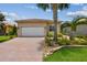 Charming single-story home with a well-manicured lawn, brick driveway, and lush tropical landscaping at 5103 Shady Stone Pl, Wimauma, FL 33598